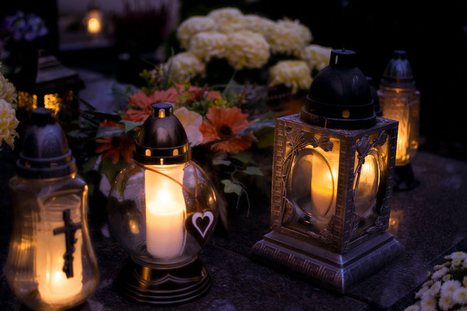 A floral arrangement placed on a dark surface featuring white and peach-colored flowers, including large hydrangeas and smaller daisies, complemented by greenery. Surrounding the arrangement are sever